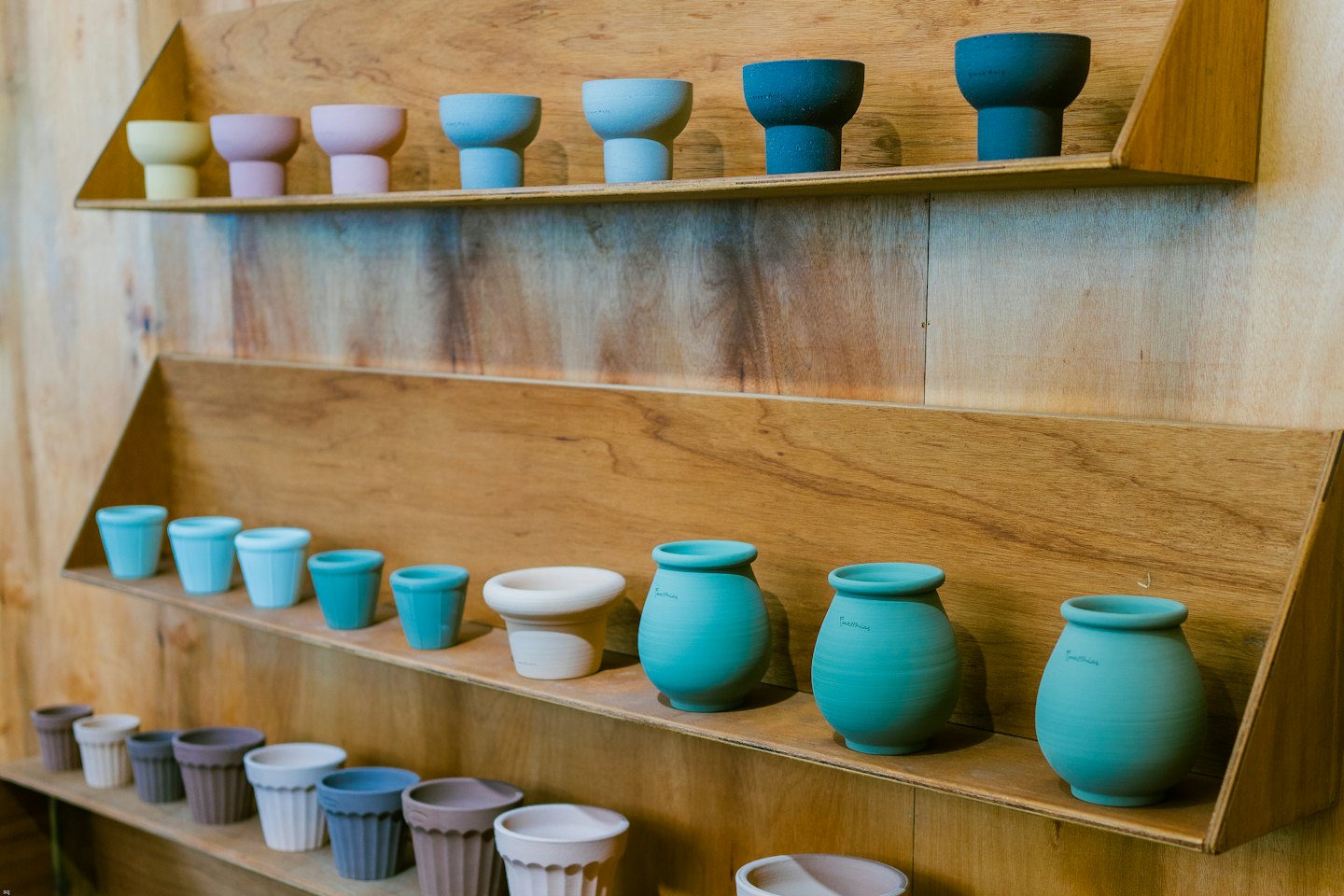 Assorted ceramic pots and vases displayed on wooden shelves.