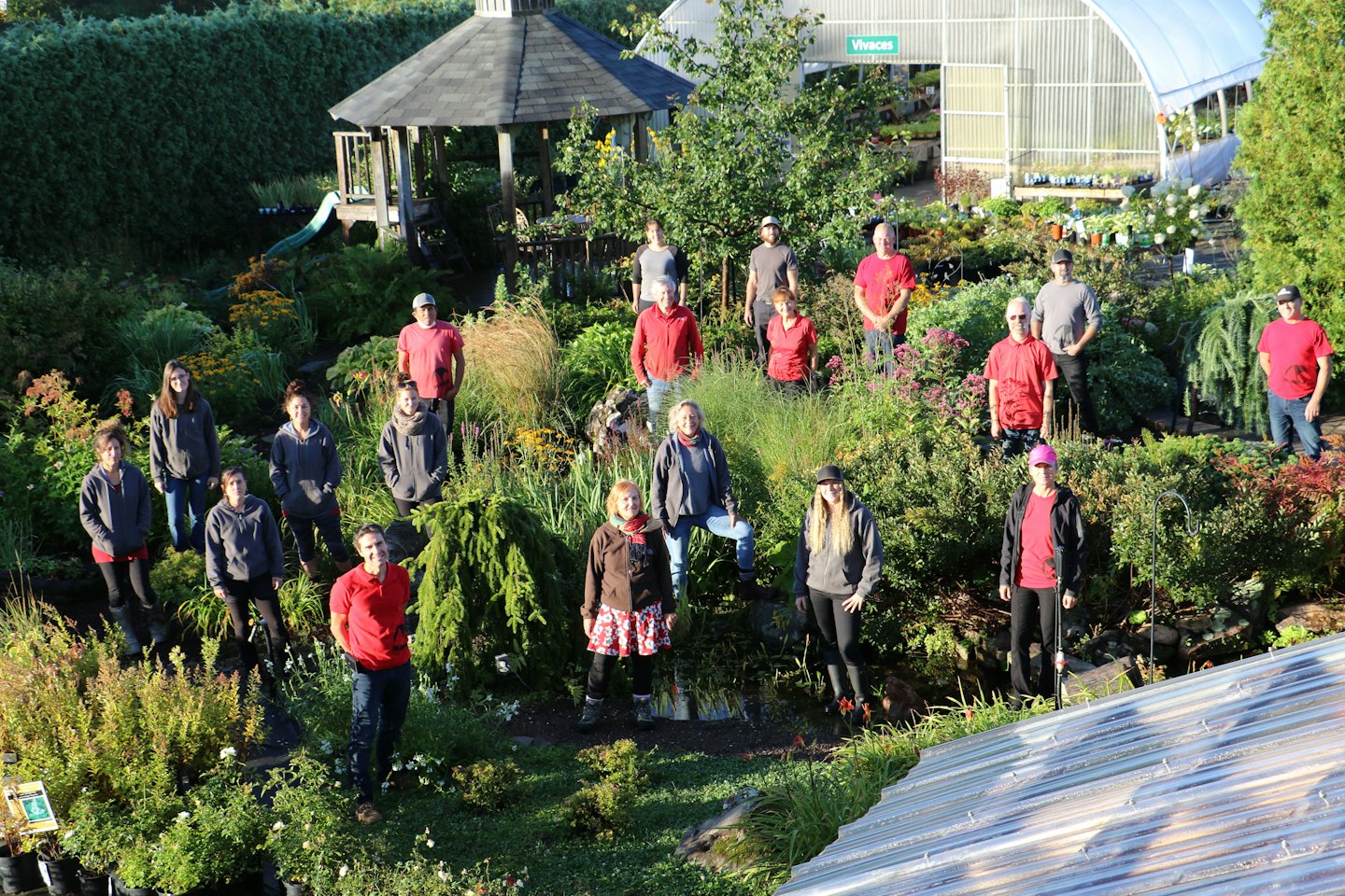 A large team of employees poses together in a garden center.